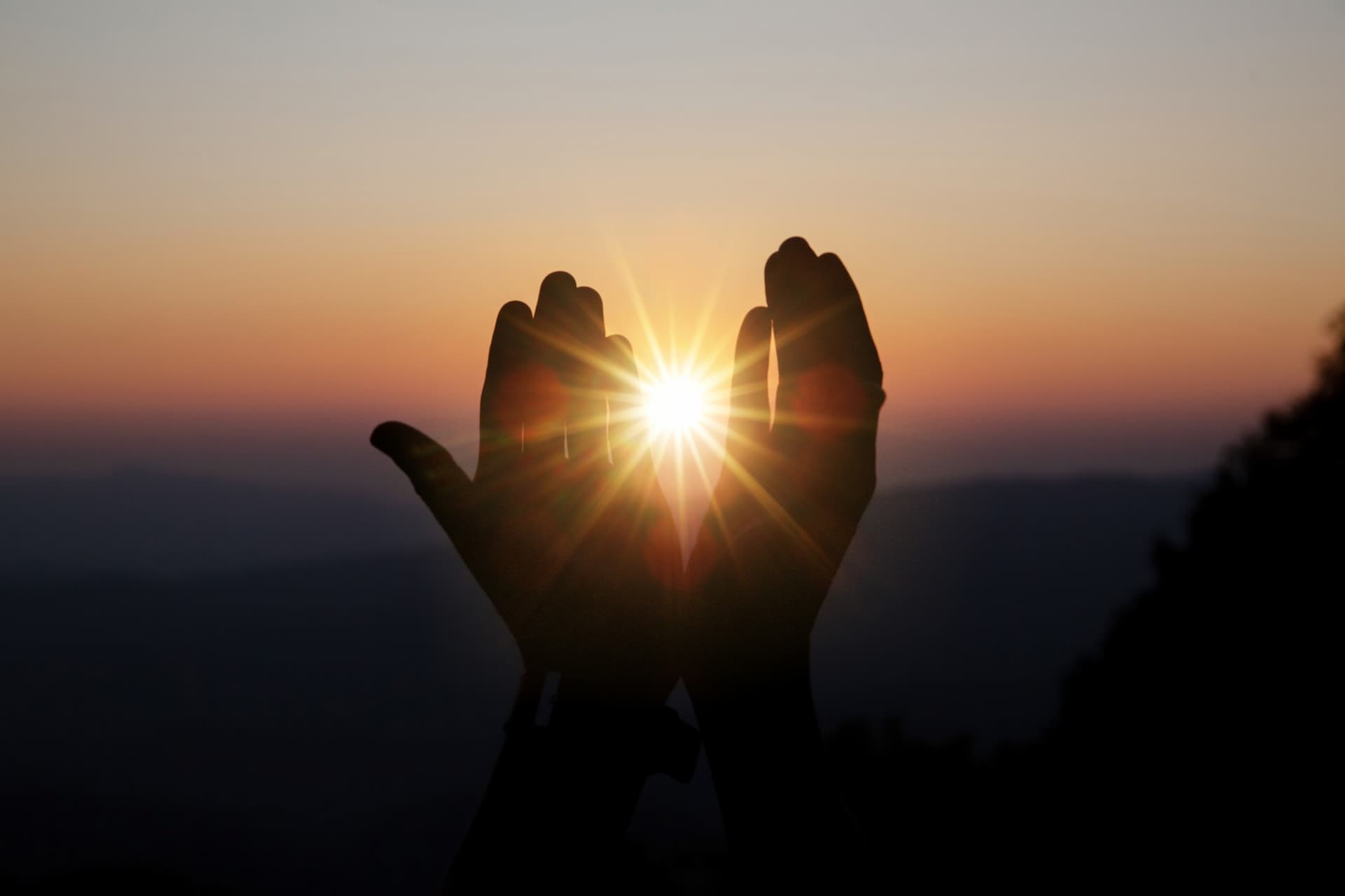 spiritual prayer hands over sun shine with blurred beautiful sunset